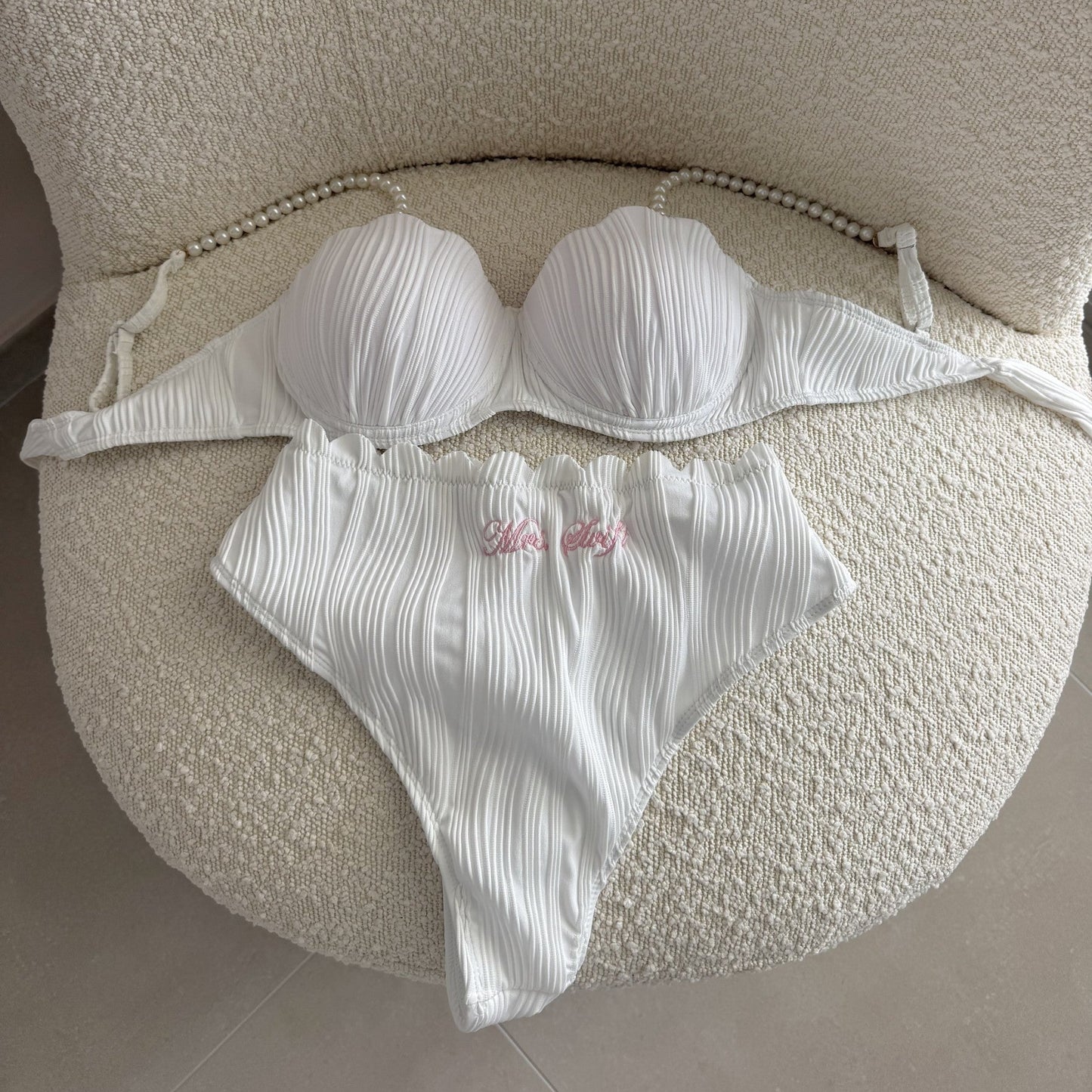 White bikini set on a textured beige surface