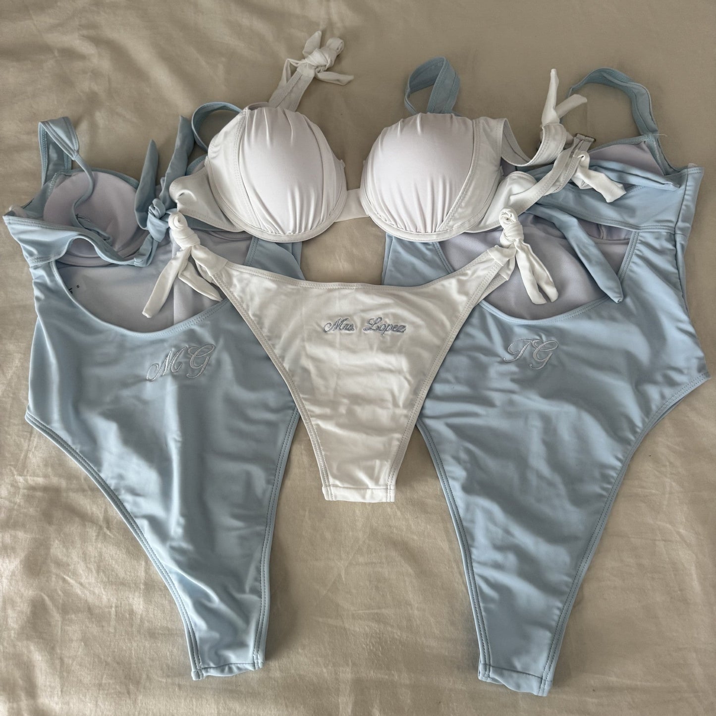 Bikini set with white top and light blue bottoms on a beige surface
