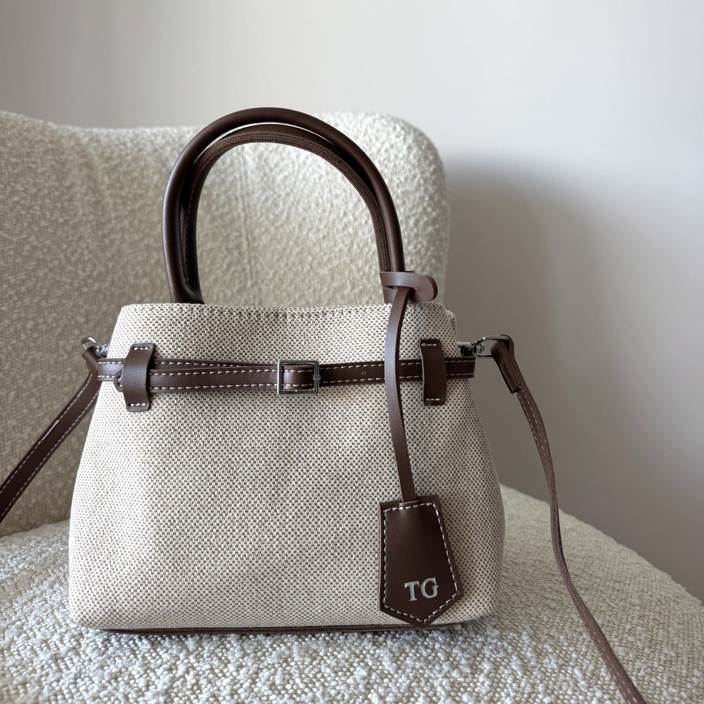 Beige handbag with brown accents on a textured surface