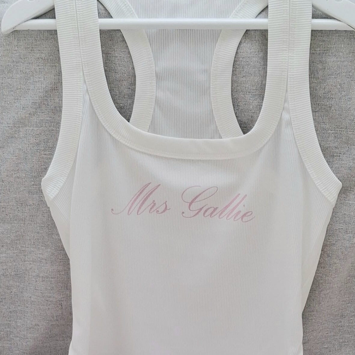 White tank top with 'Mrs Galle' text on a gray surface