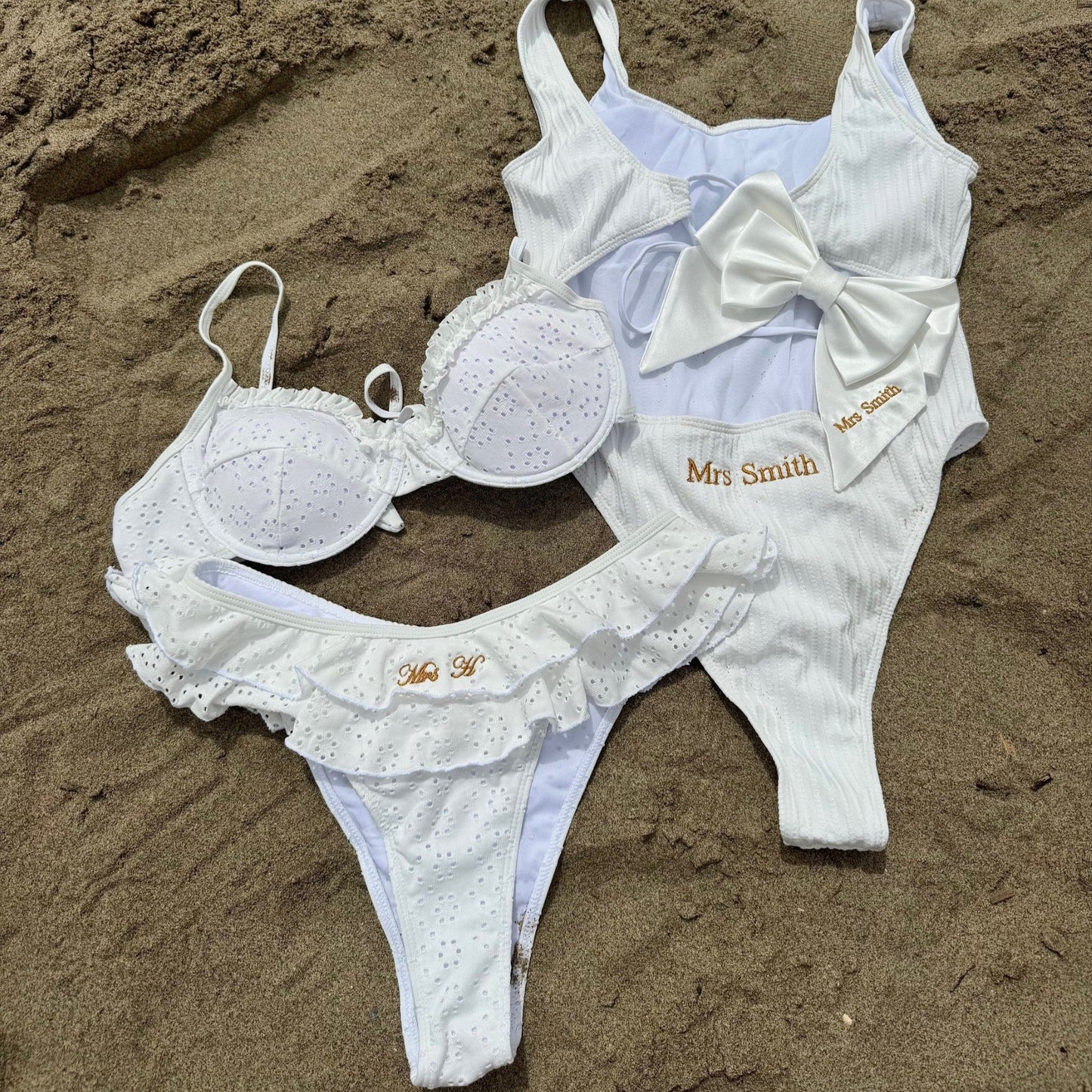 White swimsuit with 'Mrs Smith' branding on sand