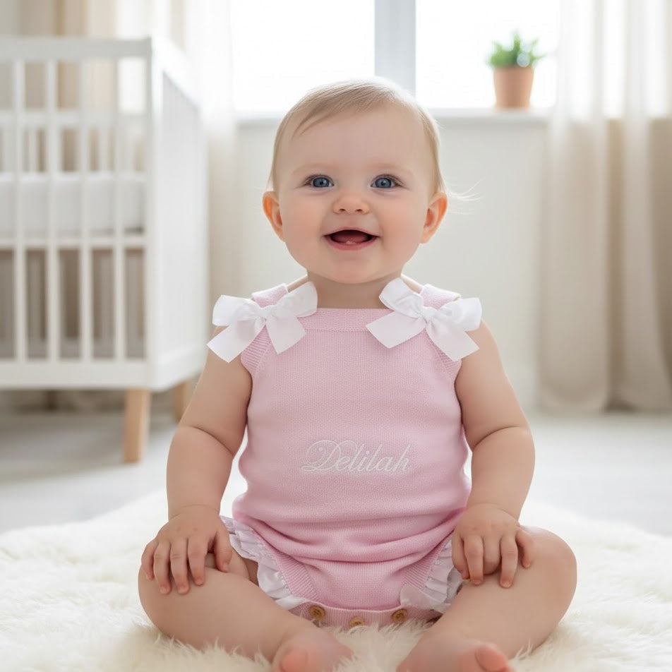 Baby wearing a pink outfit with white ruffles in a bright room