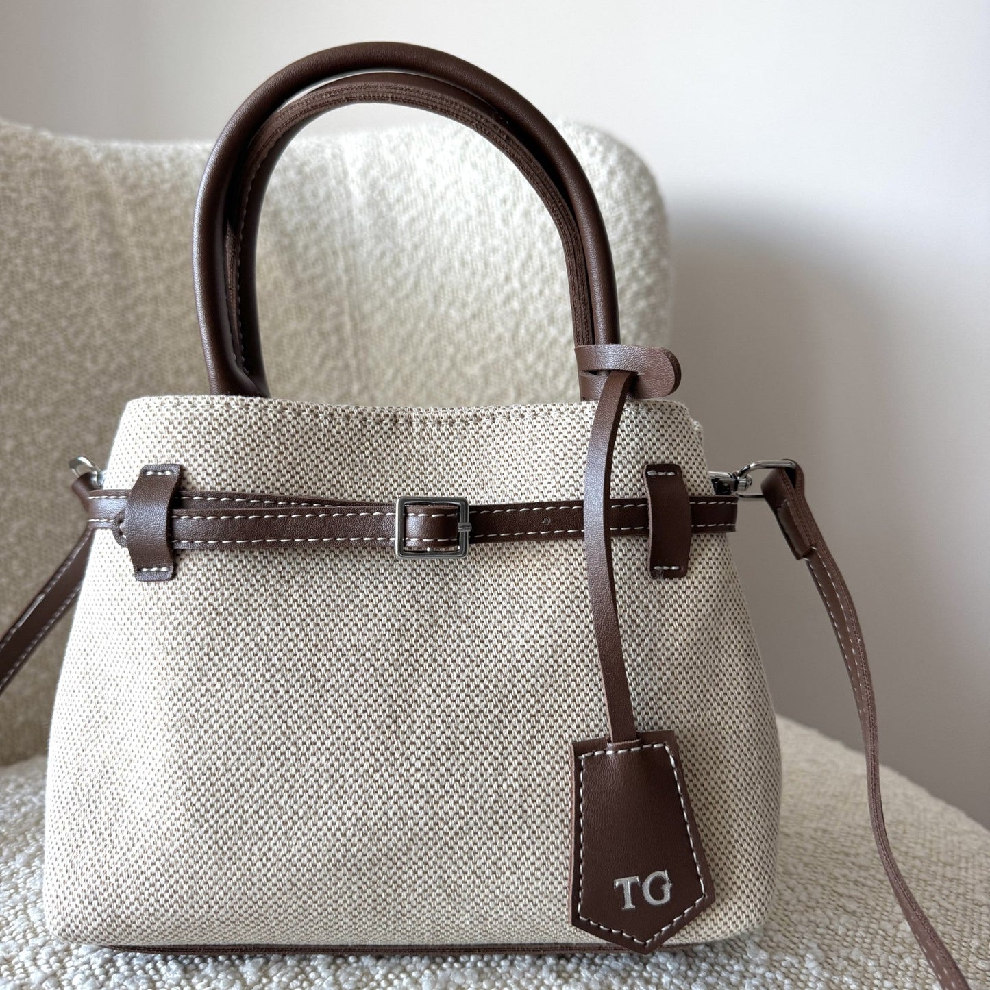 Beige handbag with brown accents on a textured surface