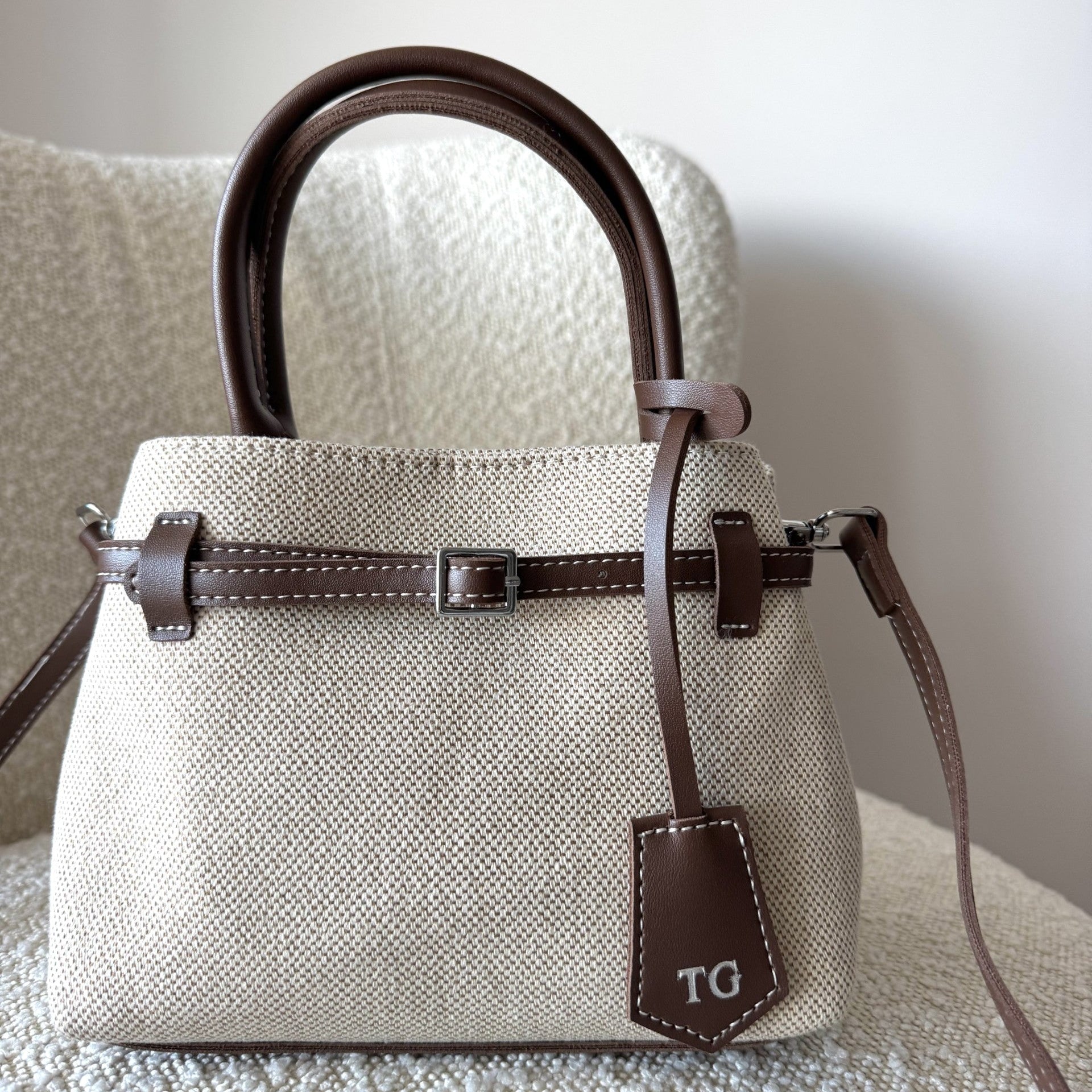 Beige handbag with brown accents on a textured surface