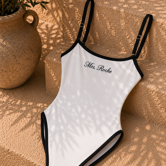 A white one-piece swimsuit with black trim and thin shoulder straps, featuring the text 'Mrs. Roche' printed in black script on the chest.