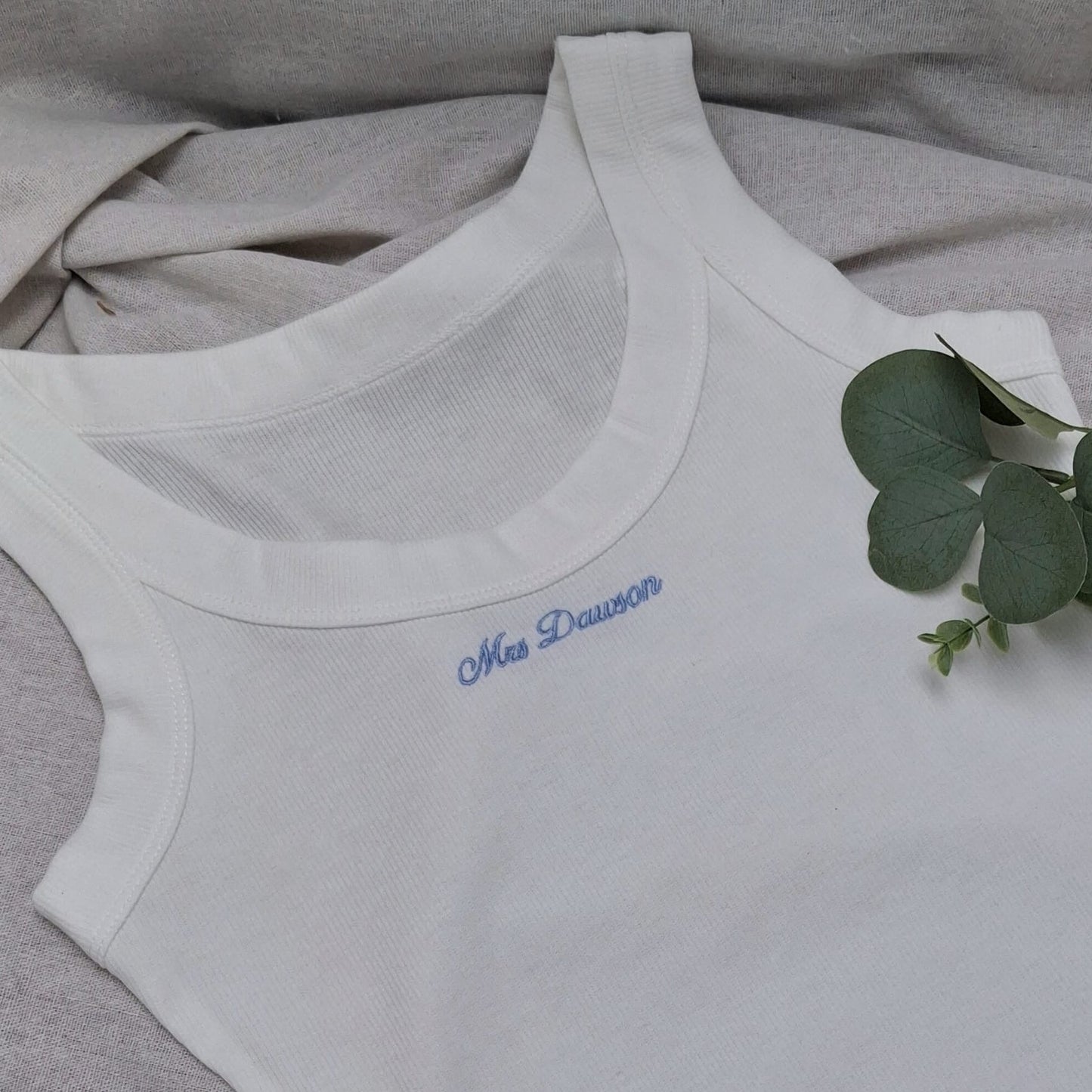 White tank top with blue text on a gray fabric background