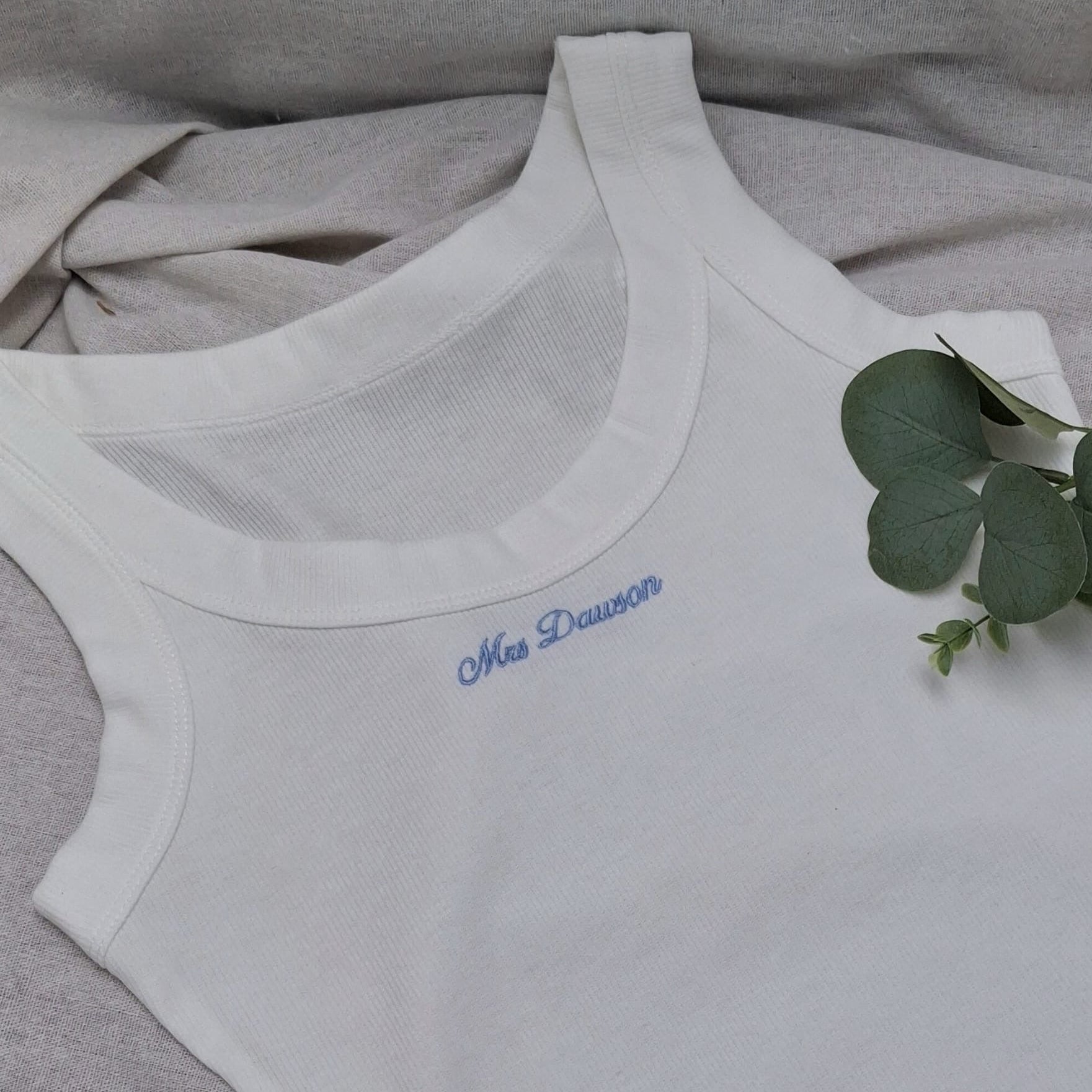 White tank top with blue text on a gray fabric background