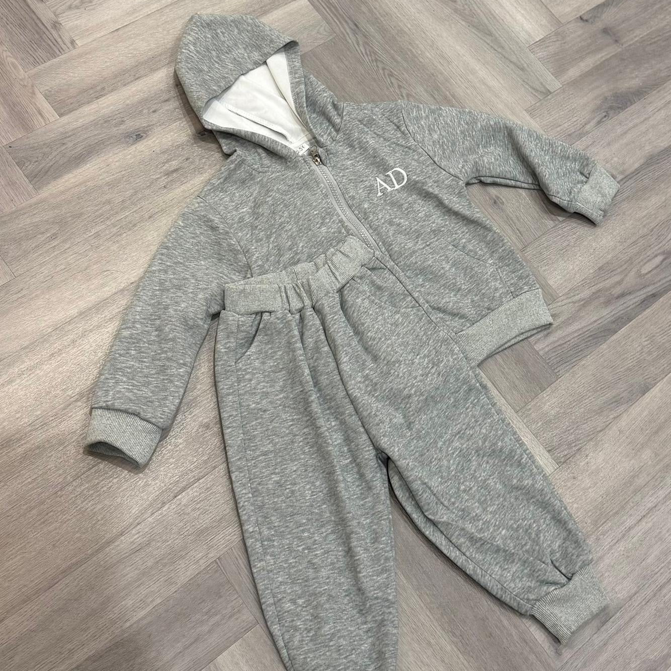 Gray tracksuit with a brand logo on a wooden floor
