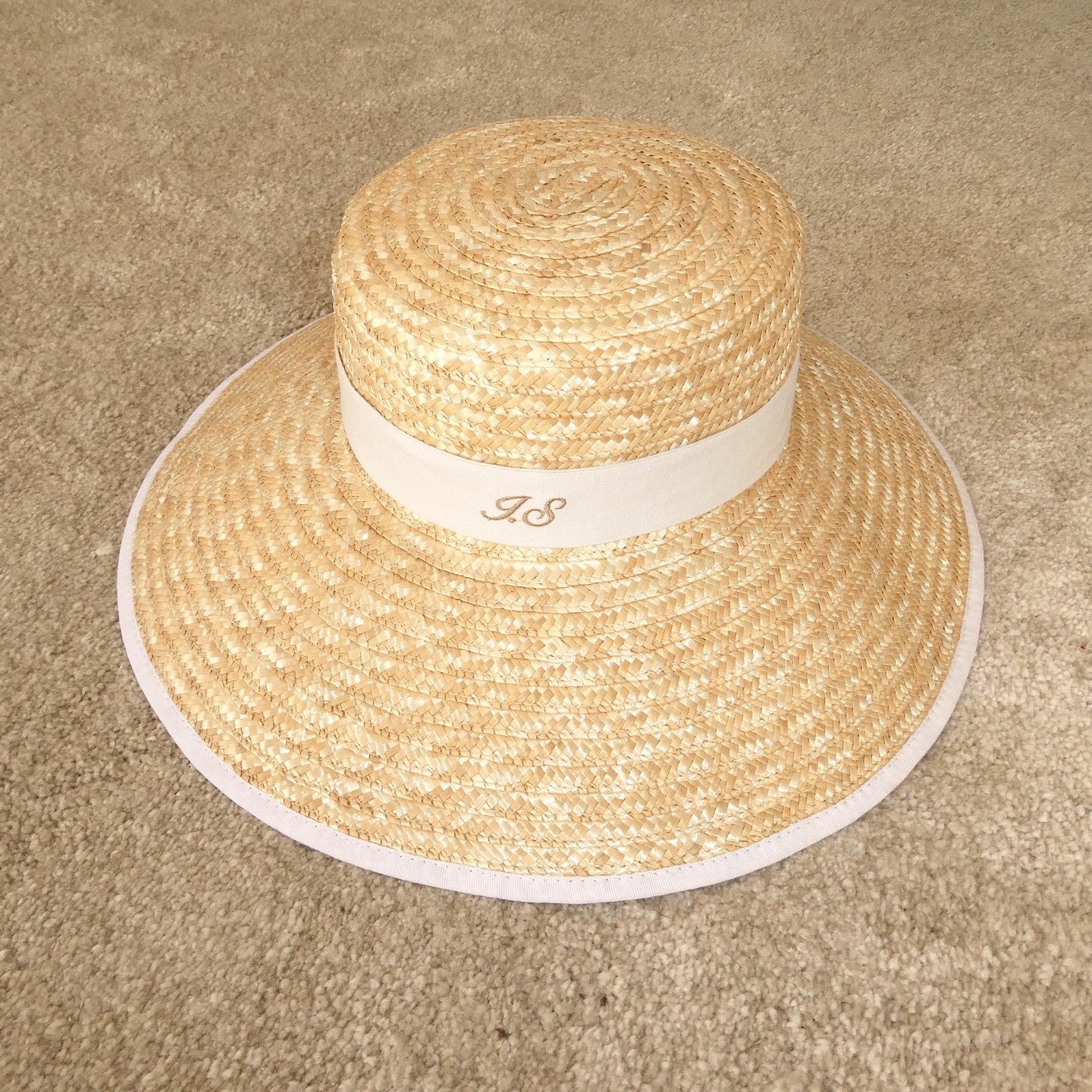 Woven straw hat with a white band on a beige carpet