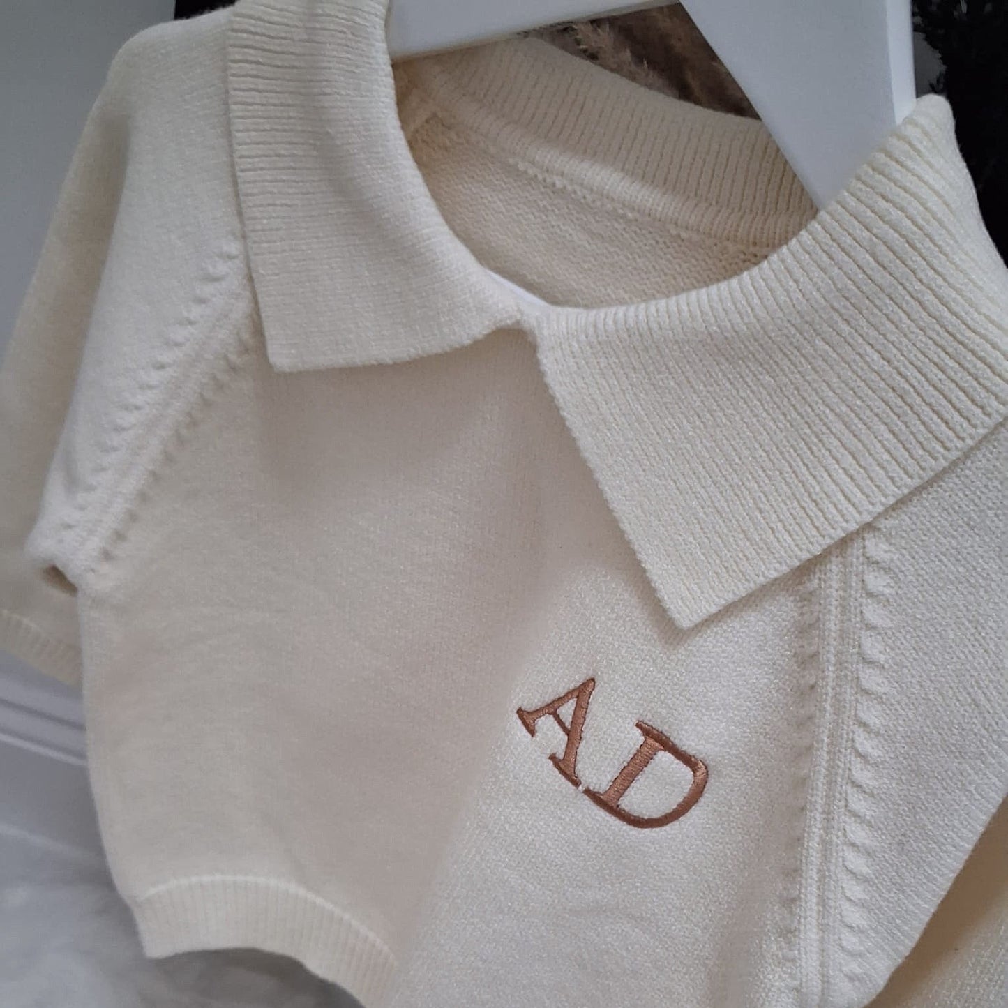 Beige sweater with 'AD' initials on a white background