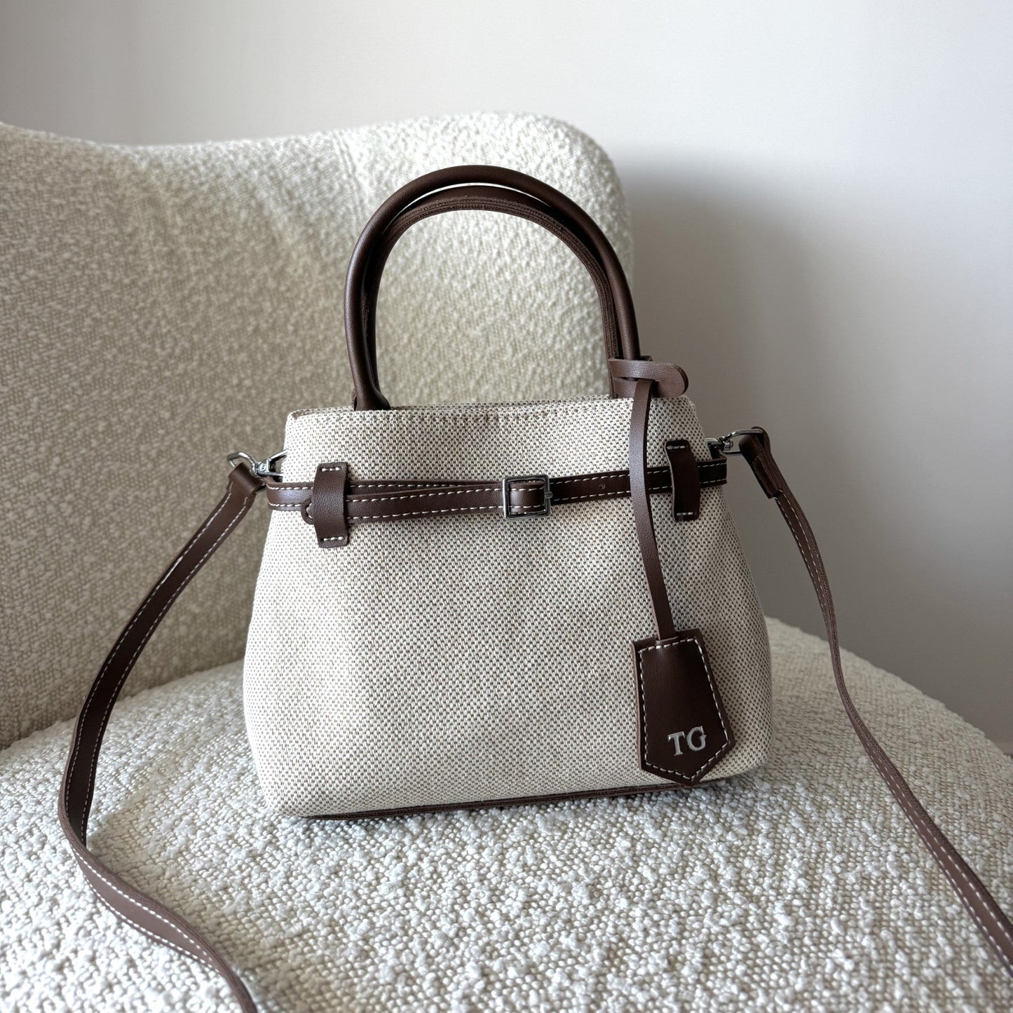 White handbag with brown accents on a textured surface