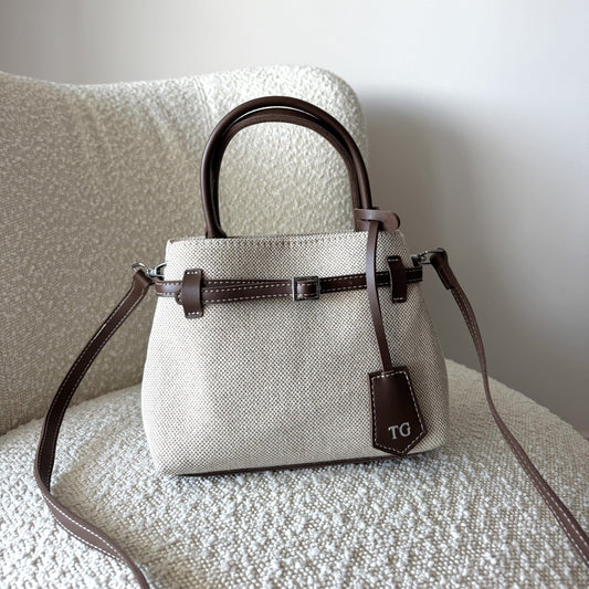 White handbag with brown accents on a textured surface