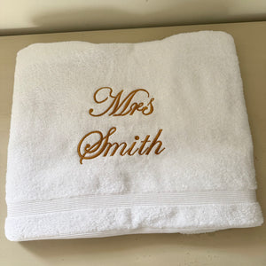 White towel with 'Mrs Smith' embroidered in gold on a beige background