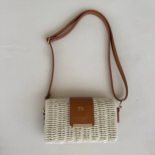 Woven handbag with brown strap and leather patch on a light gray background