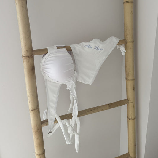 White bikini on a wooden ladder against a plain wall