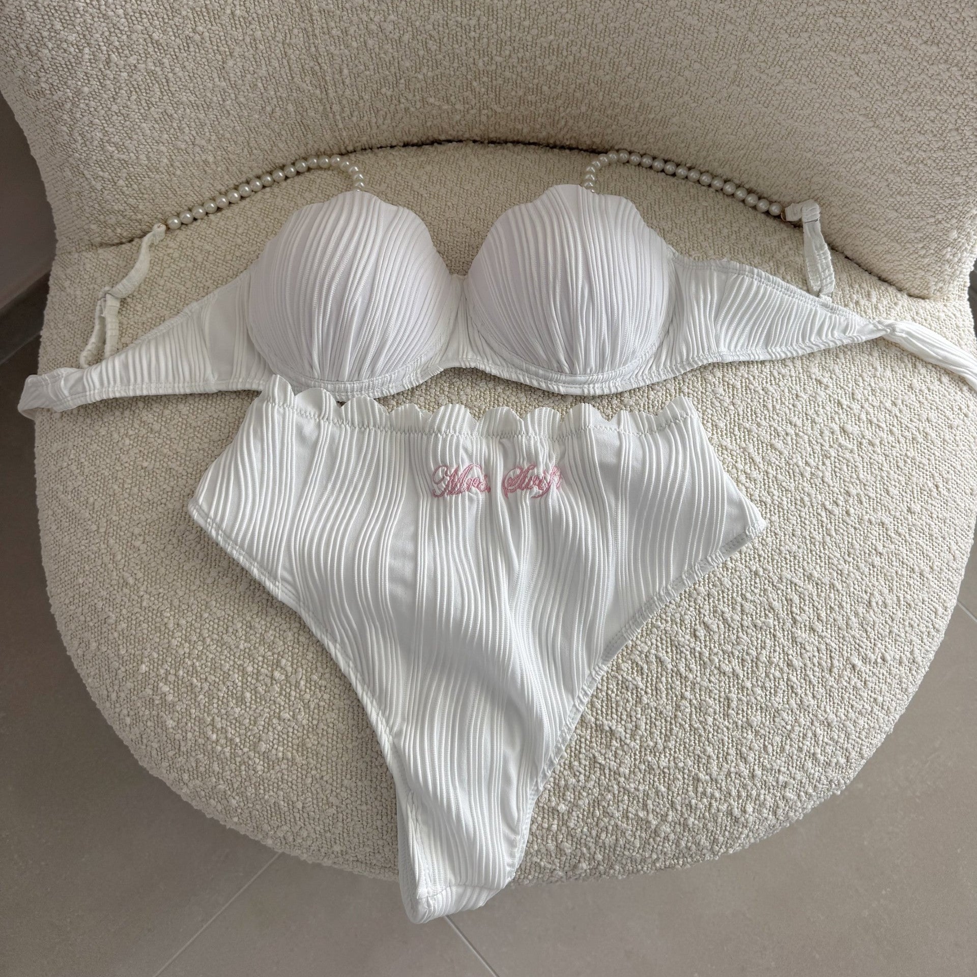 White bikini set on a textured beige surface