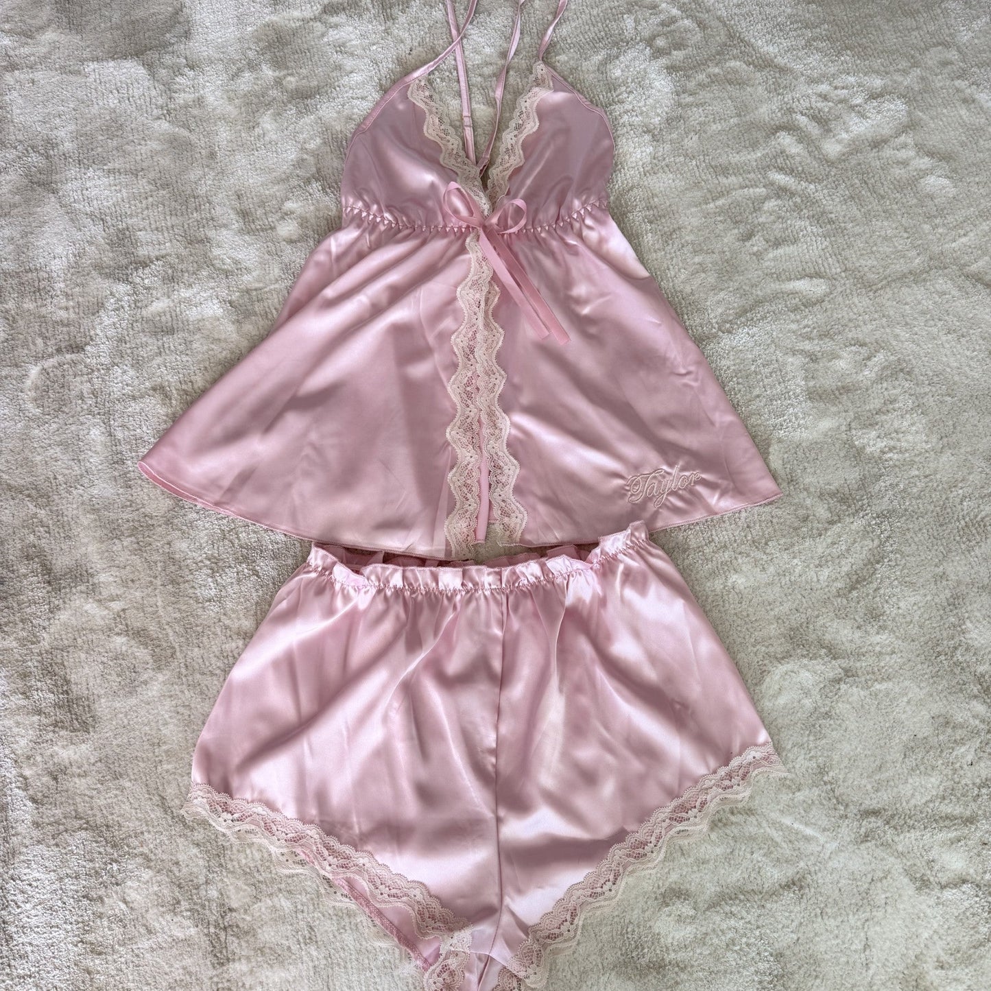 Pink satin lingerie set with lace details on a textured surface