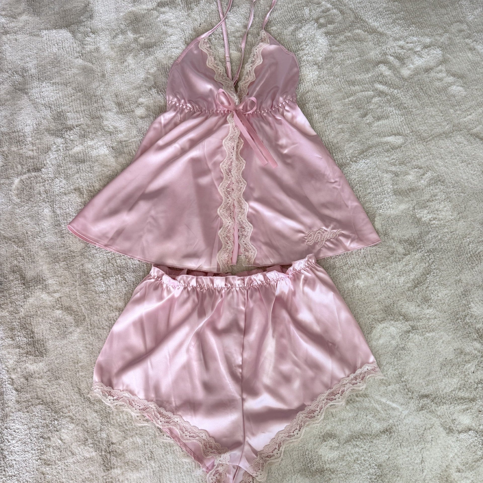 Pink satin lingerie set with lace details on a textured surface