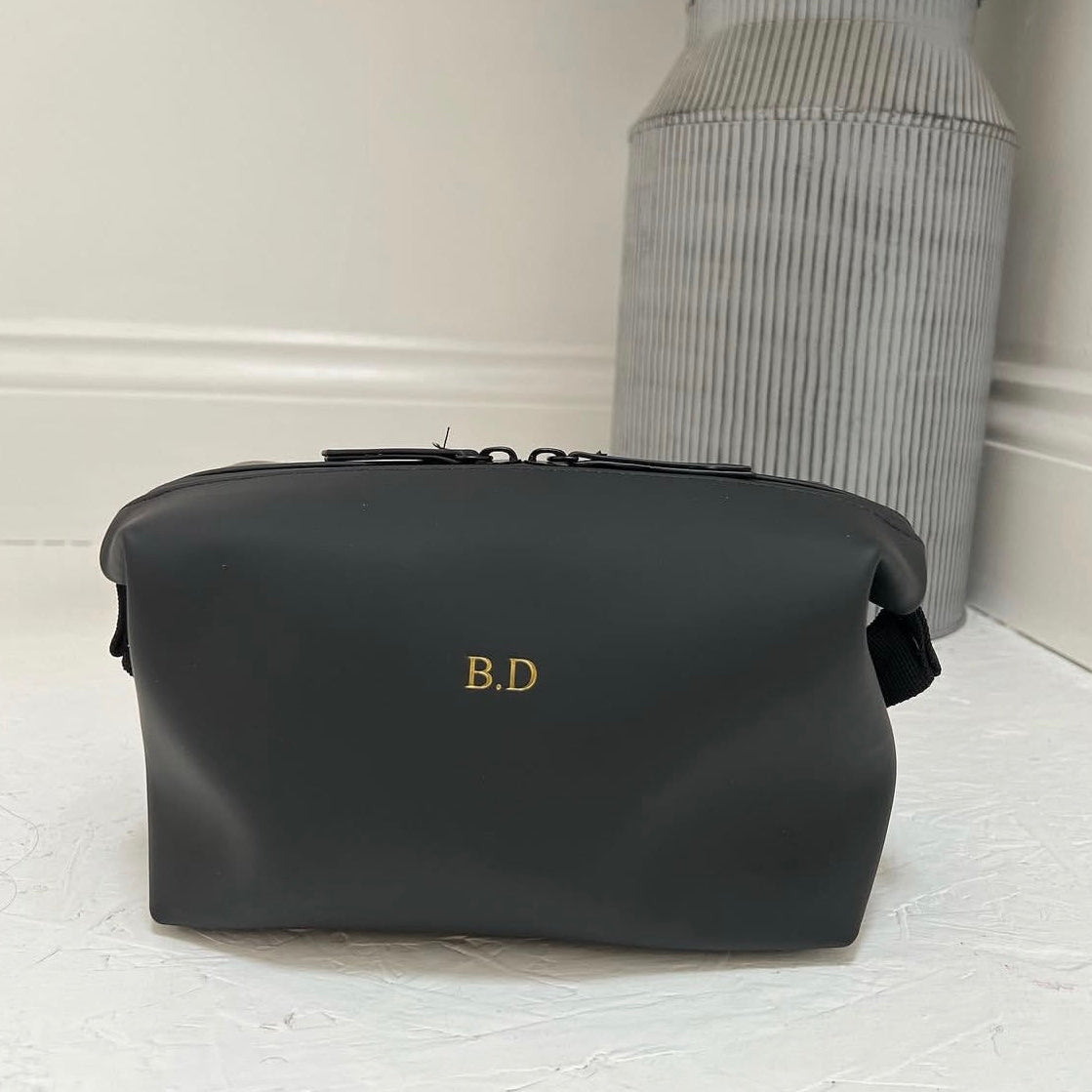 Black bag with 'B.D.' initials on a light wooden surface