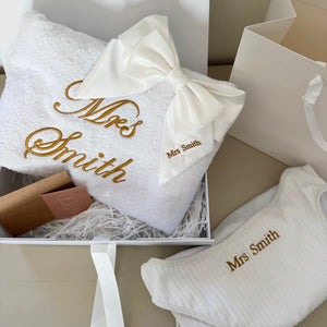 White towel with 'Mrs Smith' embroidery and matching swimwear in a gift box.