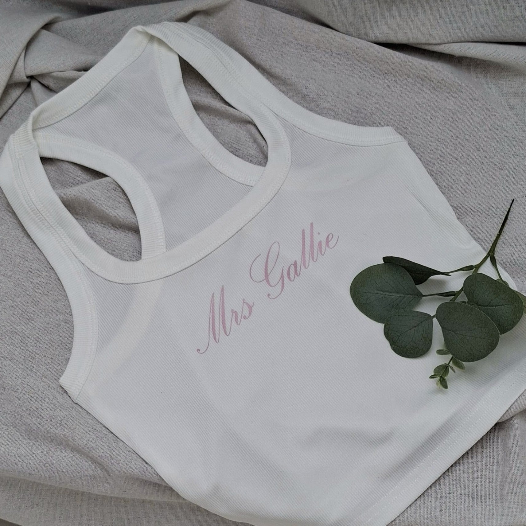 White tank top with 'Mrs. Gallie' text on a gray fabric background