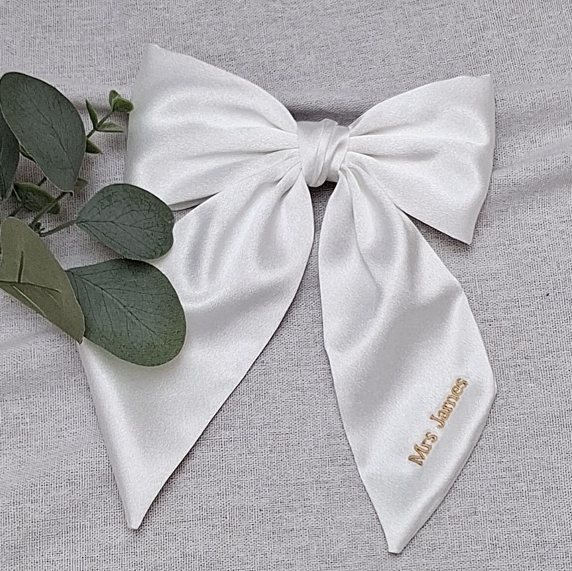 White bow with 'Mrs. Jones' embroidery on a gray background