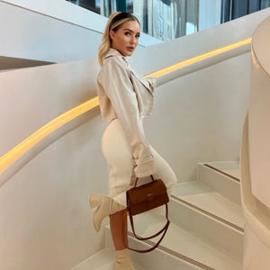 Woman in a beige coat and boots holding a brown handbag on a modern staircase. Personalised brown handbag