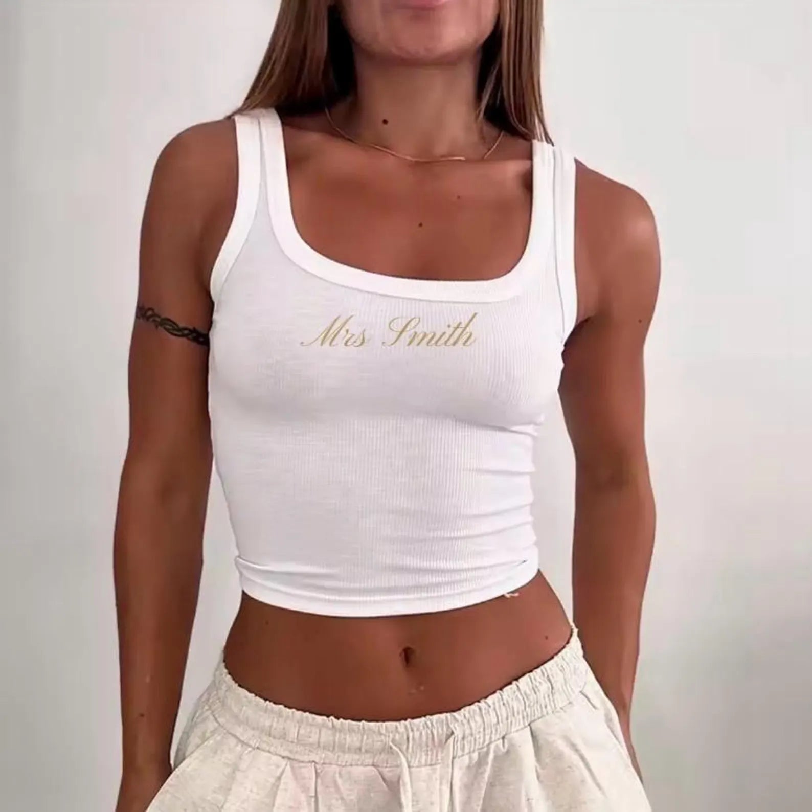 Person wearing a white tank top with 'Miss Smith' printed on it against a plain background