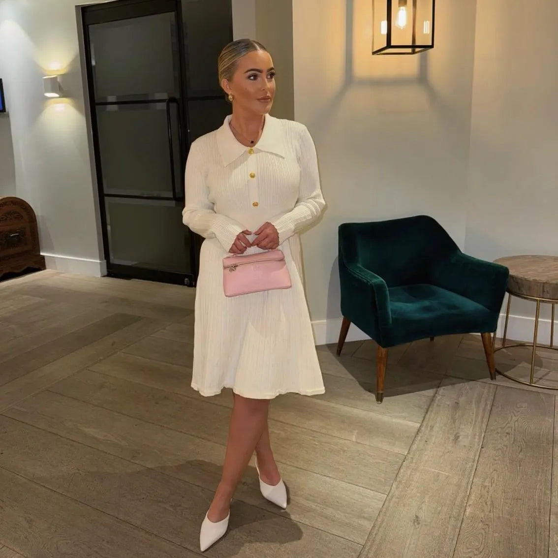 Woman in a white dress with a pink bag in an indoor setting