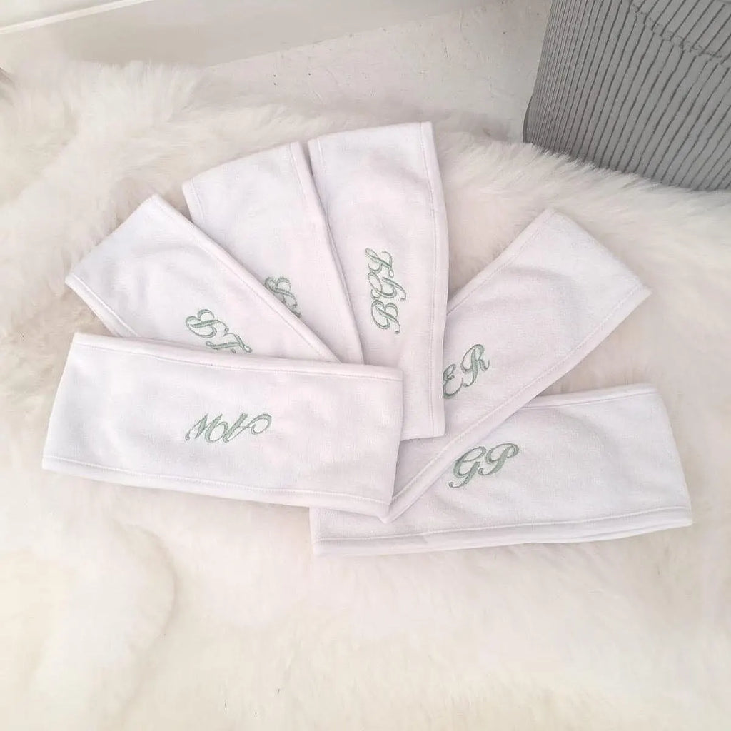 Set of white headbands with embroidered initials on a light background