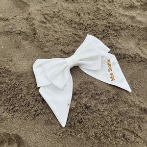 White bow with 'Mrs Smith' label on sand