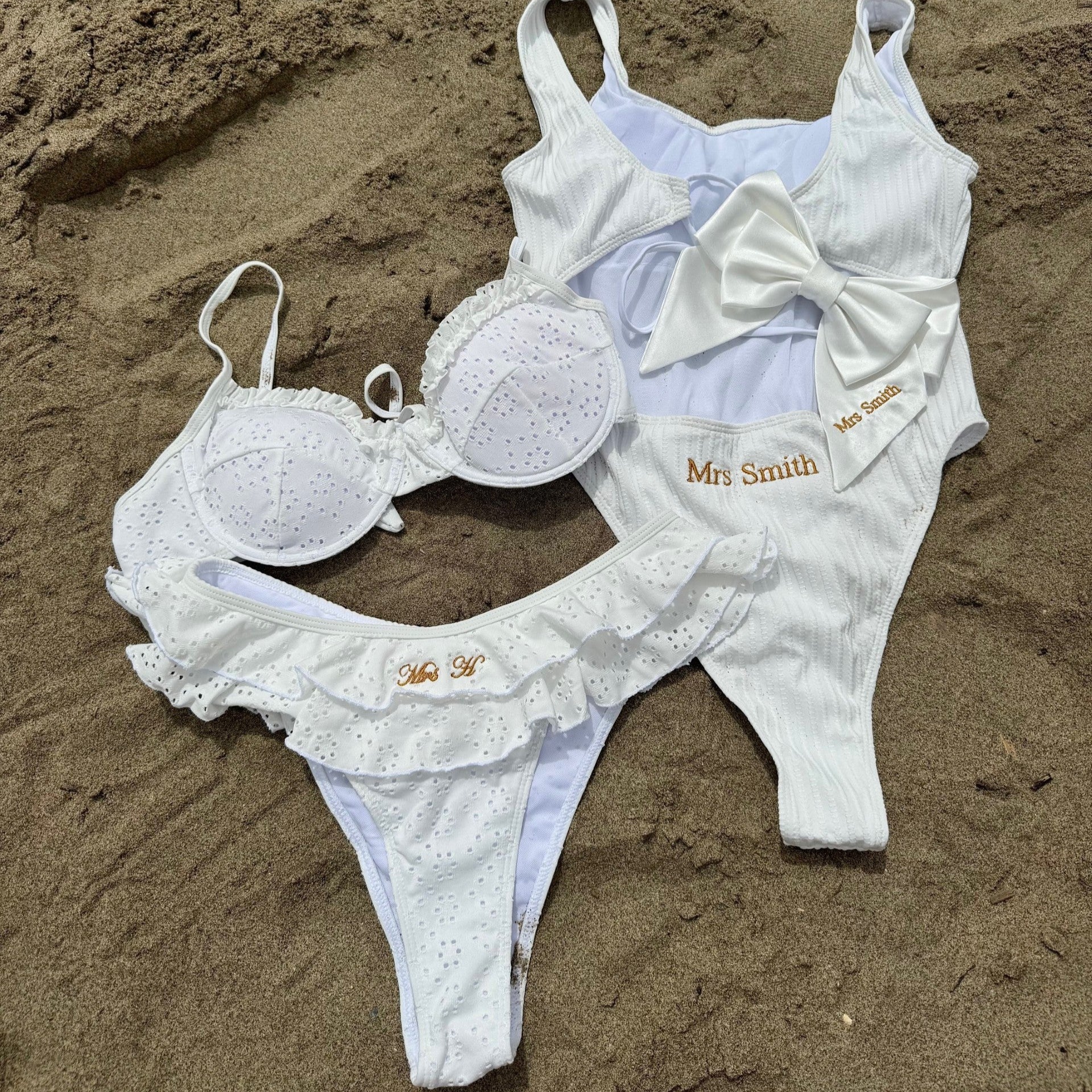 White swimsuit with 'Mrs Smith' branding on sand