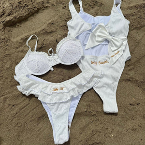 White swimsuit with 'Mrs Smith' branding on sand