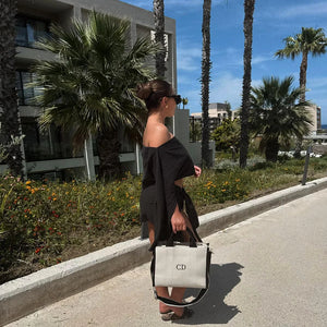 Woman walking on a sidewalk with palm trees and buildings in the background with personalised tote bag
