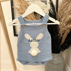 Blue knitted romper with bunny design and 'Archie' text on a hanger.
