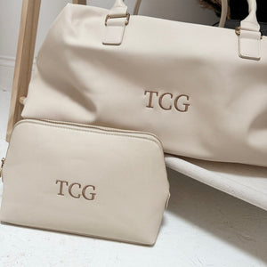 Beige weekender with TCG initials close up and matching washbag