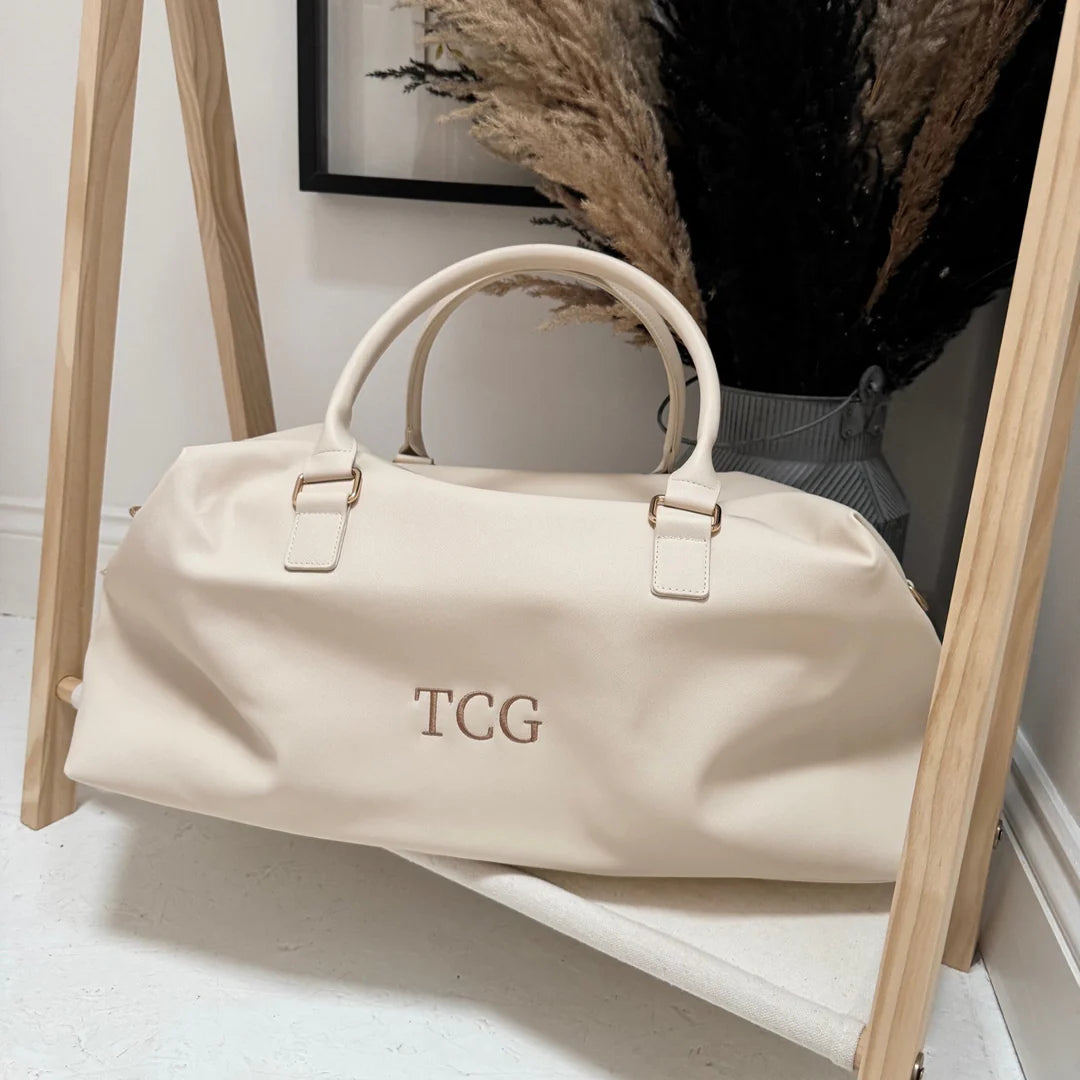 beige weekend bag with the initials TCG on it