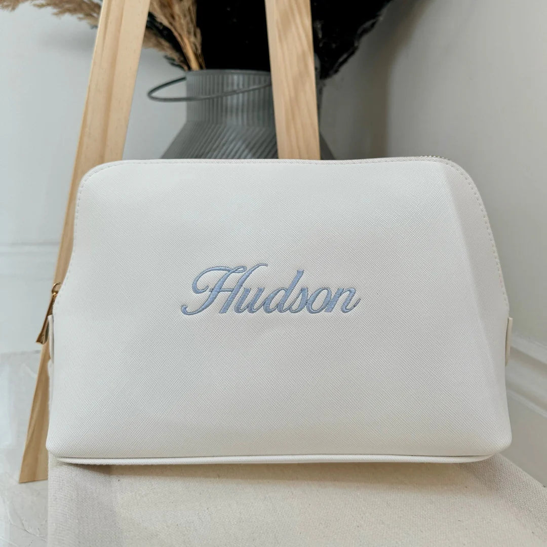 White pouch with 'Hudson' embroidery on a light background
