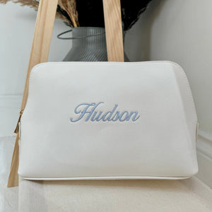 White pouch with 'Hudson' embroidery on a light background