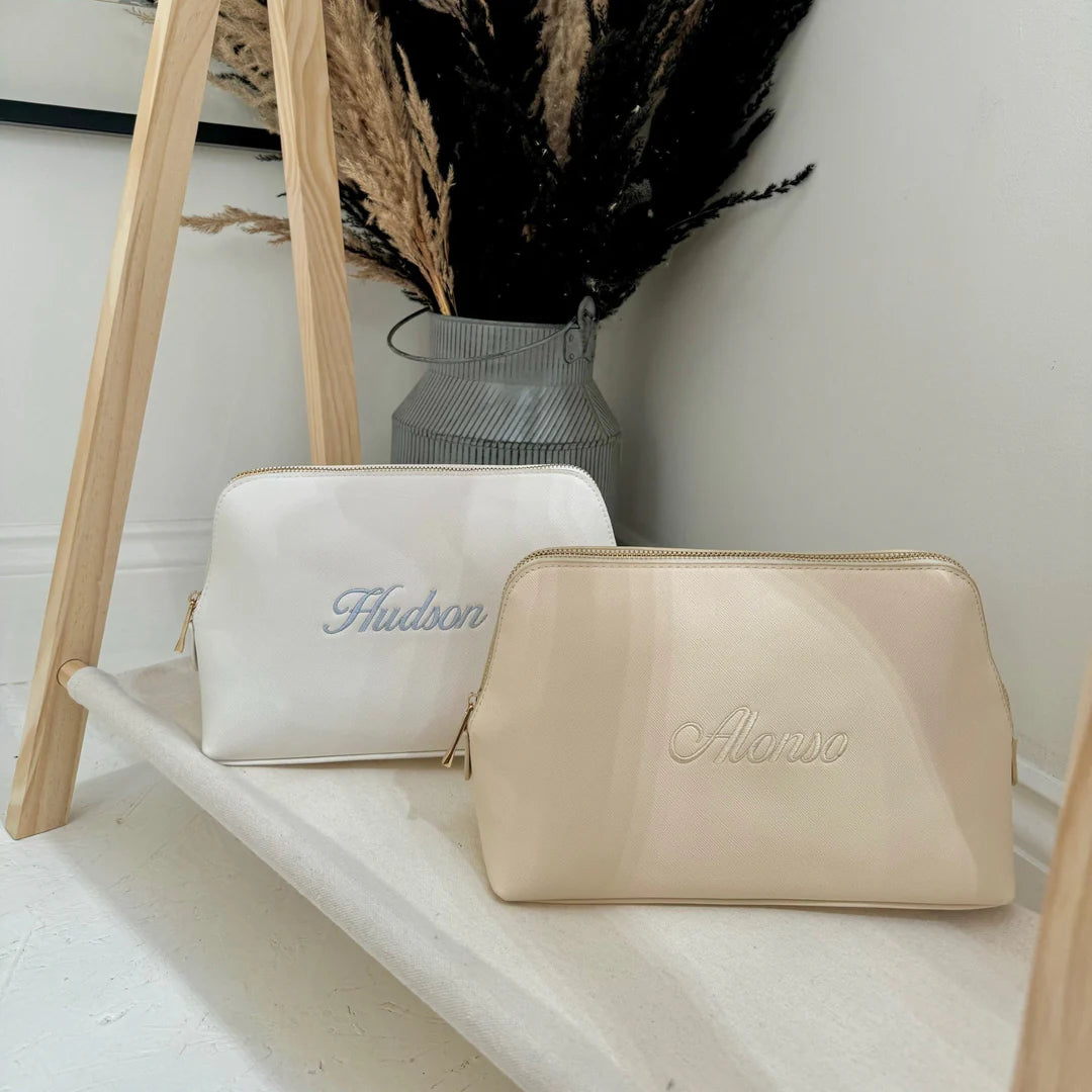 Two cosmetic bags, one white and one beige, with 'Hudson' and 'Alonso'