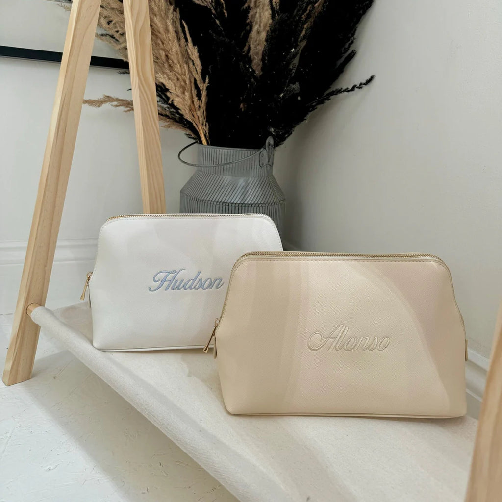 Two cosmetic bags, one white and one beige, with 'Hudson' and 'Alonso'