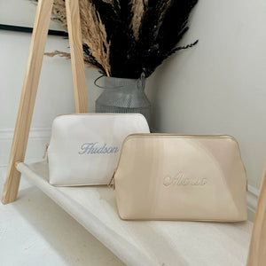 Two cosmetic bags, one white and one beige, with 'Hudson' and 'Alonso'