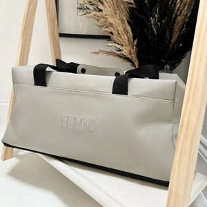 Grey weekend bag with white initials on it 