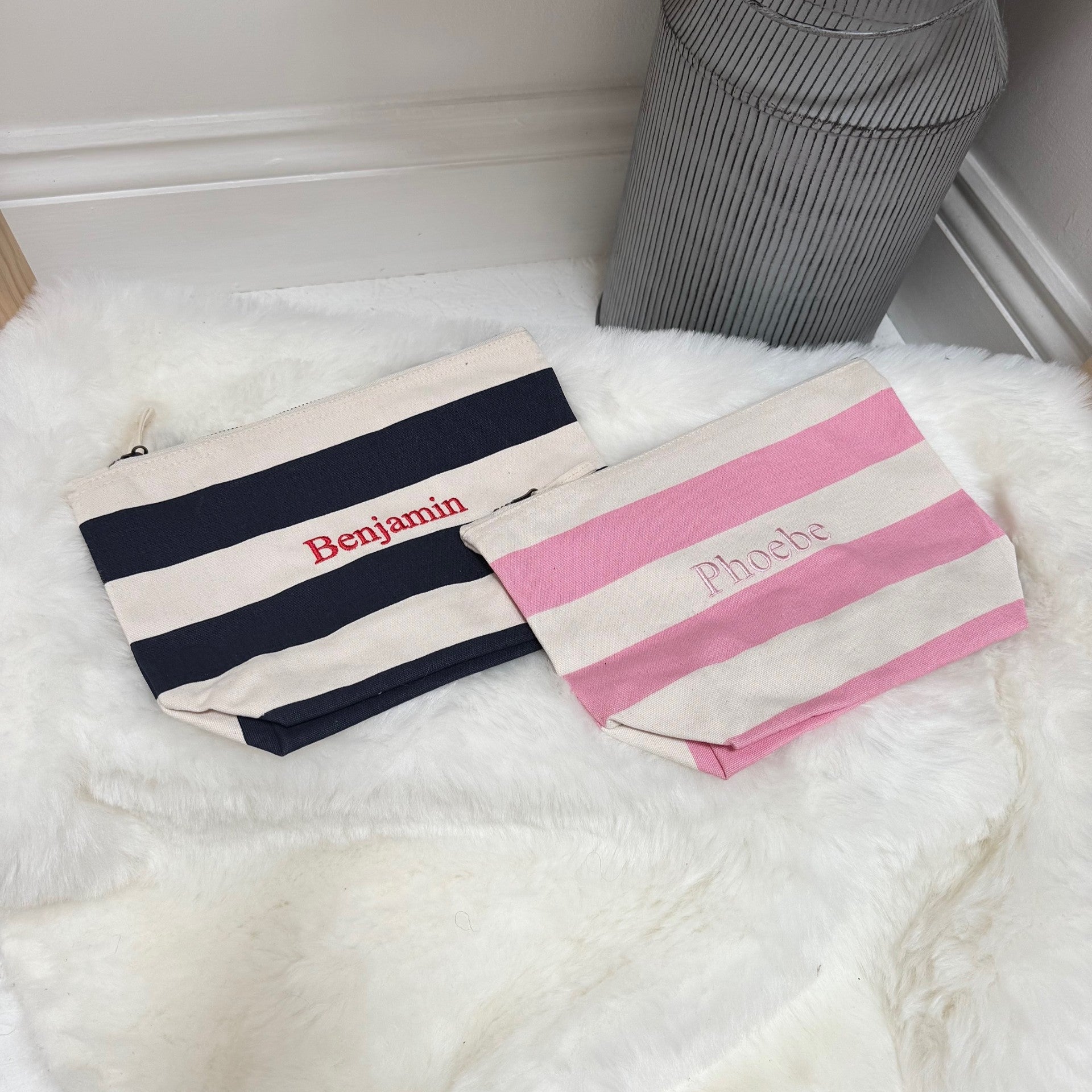 Two striped pouches with names printed on them, placed on a white surface.