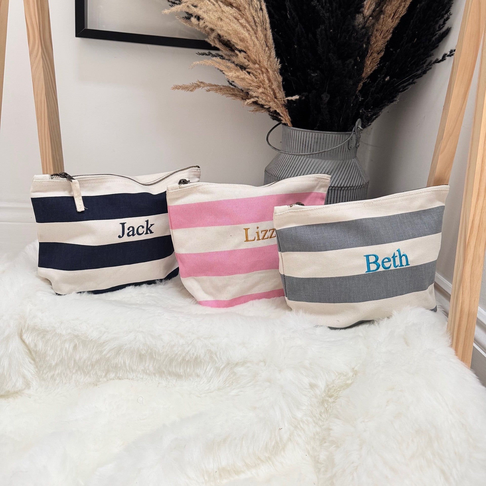 Three bags with names 'Jack', 'Lizzy', and 'Beth' on a white surface with decorative plants in the background.