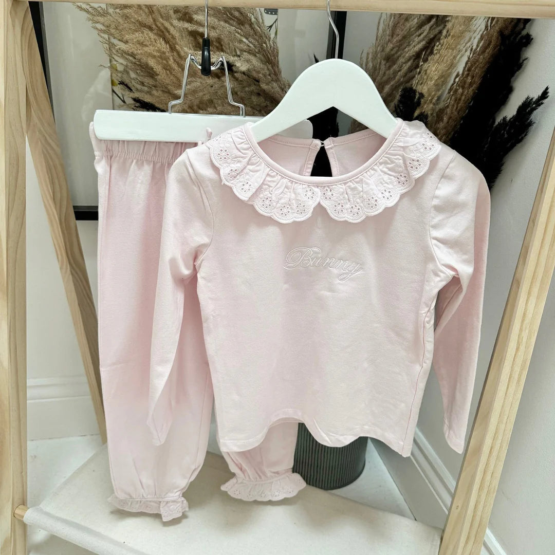 Pink blouse with lace collar and matching pants on a hanger.