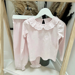 Pink blouse with lace collar and matching pants on a hanger.