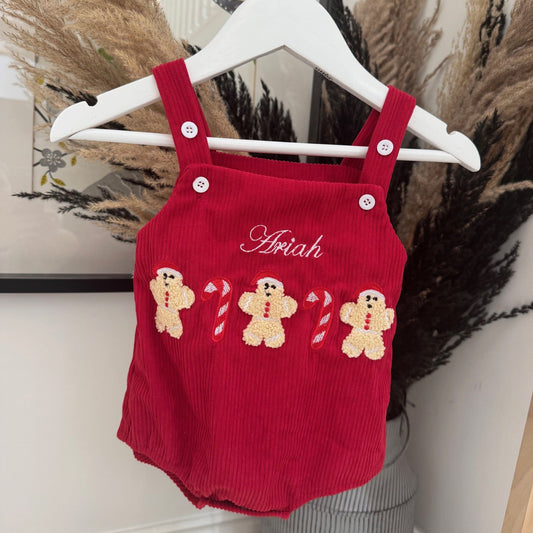 Red baby romper with gingerbread design and 'Ariah' embroidery on a hanger.