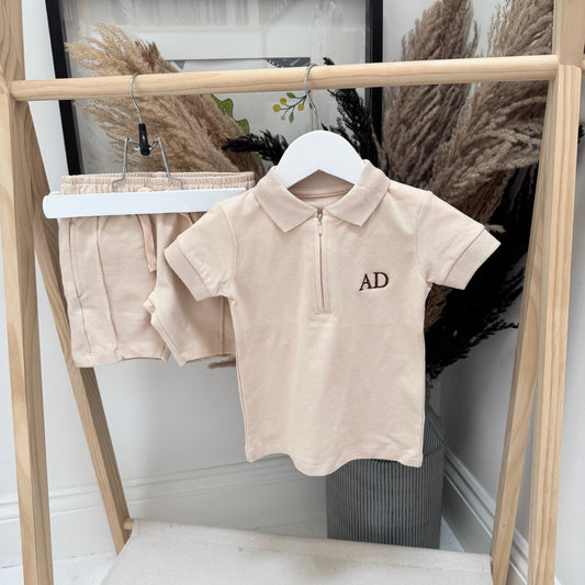 Beige polo shirt with 'AD' logo on a hanger against a neutral background