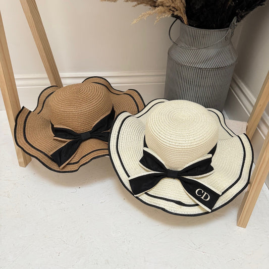 Two straw hats with black bows on a light-colored floor.